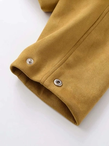 Gros plan d'une veste en daim jaune moutarde avec des boutons-pression en métal argenté
