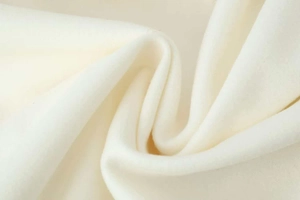 Detail of soft cream wool fabric texture with natural folds on a long winter coat