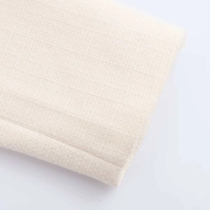 Detailed close-up of beige tweed fabric texture and high-quality stitching on a jacket