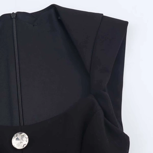Detail of black romper featuring hidden back zipper and crystal rhinestone button