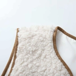 Detail of cream sherpa vest featuring premium brown faux suede piping and soft texture