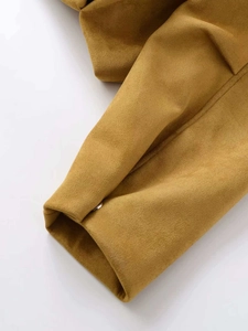 Détail du poignet d'une veste en daim moutarde avec couture fine et bouton en métal