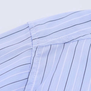 Macro shot of vertical stripes and high-quality shoulder seam stitching on blue shirt