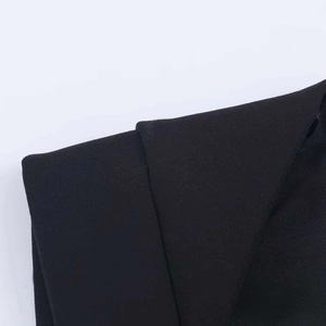 Detail shot of black structured jumpsuit with overlapping seams and textured fabric finish