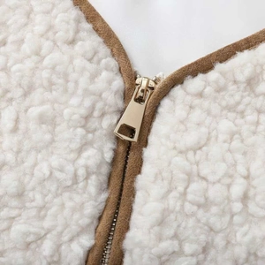 White faux shearling vest with brown fabric trim and shiny gold metal zipper detail