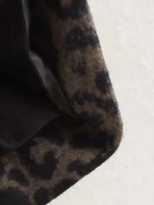 Detailed view of leopard print coat fabric with thick texture and black inner lining