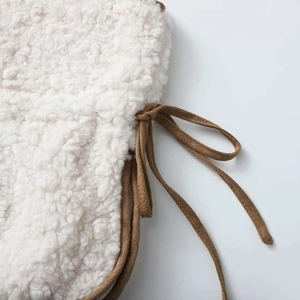 White faux shearling vest with brown suede tie string detail shown in a close-up view