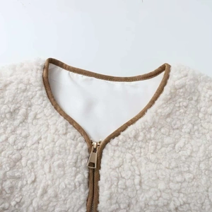 Detail view of cream white sherpa vest with brown piping and light gold metal zipper