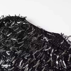 Close-up of black and silver sequins with fringe details on a V-neck dress garment
