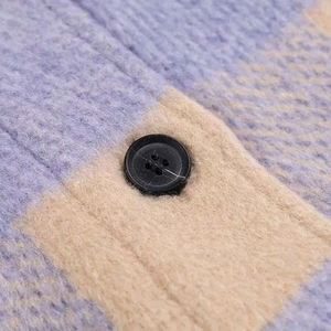 Macro shot of plaid brushed fabric with purple and beige patterns and black button