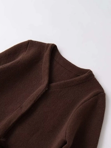 Detailed view of the dark brown thick knit cardigan with a clean collarless neckline