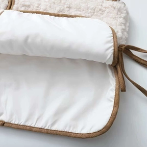 Detailed view of cream faux shearling vest featuring brown trim and side tie-up details