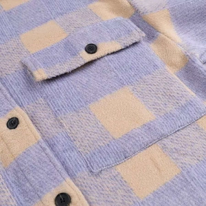 Close-up of thick plaid wool fabric featuring a pocket flap and a round black button