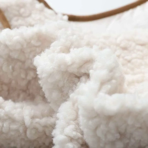 Macro detail of plush faux shearling fabric texture with brown trim on white vest