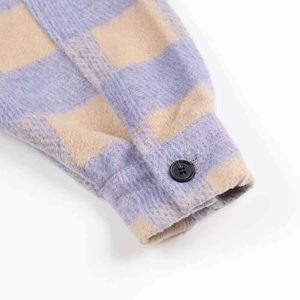 Close-up of thick flannel cuff with lavender plaid pattern and black button detail