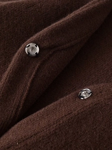Detail of silver snap button on dark brown faux fur knitwear with macro texture