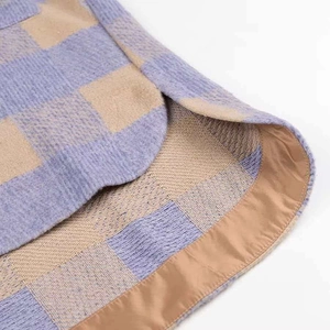 Detailed close-up of curved hem and plaid tweed fabric on a loose checkered jacket
