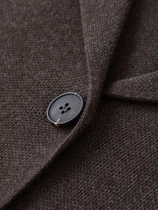 Detailed macro view of charcoal grey knit fabric with a matte black four-hole button