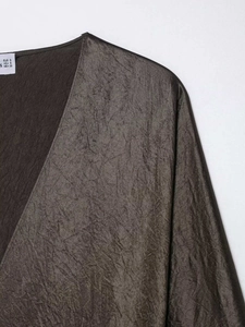 Detailed close-up of bronze silk satin fabric texture with V-neckline and size labels