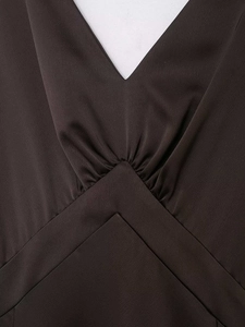 Detailansicht des tiefen V-Ausschnitts und der Taillenfalten am braunen Satin-Kleid