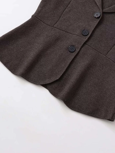 Detail view of dark grey vest with textured fabric, three buttons and curved hemline