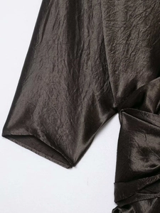 Detailed macro view of the dark brown crinkled satin fabric with elegant metallic luster