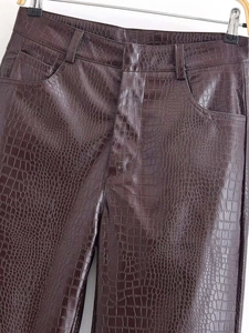 Détail du pantalon en similicuir marron foncé avec texture crocodile et poches latérales