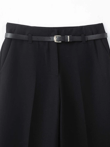 Detail einer schwarzen Hose mit weitem Bein, schmalem Gürtel und markanten Bügelfalten