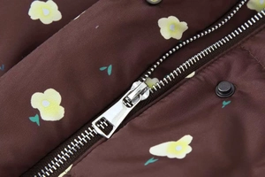 Detail of silver metal zipper and snap button on dark brown floral print coat