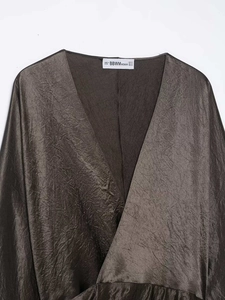 Close-up of elegant brown satin top with V-neckline and pleated metallic texture