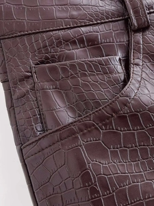 Détail du similicuir marron foncé à motif crocodile avec coutures de poche précises