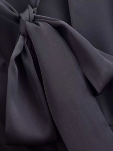 Detail of elegant black satin waist shirt featuring a large handmade bow tie design
