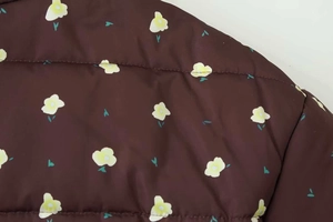 Detail of floral print on brown padded jacket featuring horizontal quilting lines