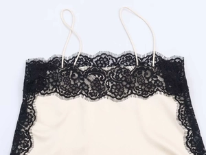 Dettaglio del pizzo floreale nero cigliato su un top a canotta in raso beige elegante