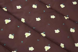 Close-up of quilted floral fabric texture with yellow flower pattern on brown background