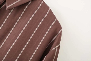 Dettaglio cucitura spalla e trama tessuto su camicia a righe verticali marrone scuro