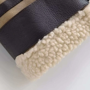 Detail aus dunkelbraunem Kieselleder und cremefarbenem Lammfell an einer Winterjacke