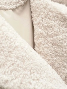Détail du tissu en peau de mouton synthétique crème et de la doublure lisse du manteau