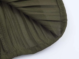 Detail of olive green pleated midi dress fabric showing fine texture and hem stitching