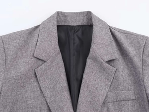 Detail of grey herringbone blazer lapel showing fine texture and neat stitching
