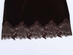 Detail of dark brown velvet fabric with intricate floral lace trim on the hemline