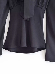 Detail view of smooth black satin fabric and bow-tie ribbon on the long sleeve shirt