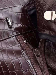 Vue macro détaillée du cuir marron foncé à motif crocodile et des ferrures argentées