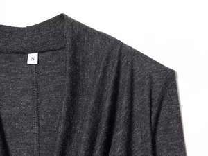 Détail du tricot chiné gris foncé avec étiquette de taille S visible sur l'encolure