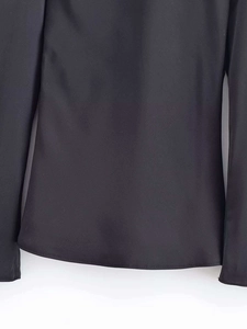 Detailed macro view of the curved hem and fine stitching on a black satin blouse