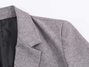 Detailed close-up of grey herringbone blazer lapel showing premium fabric and fine stitching