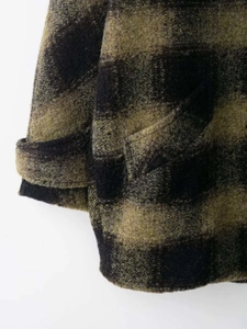 Close-up of olive green and black plaid wool coat showing thick fabric and pocket detail