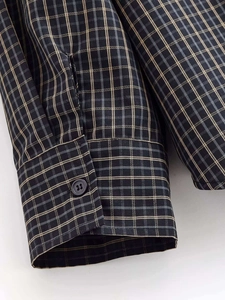 Détail du poignet d'une chemise à carreaux avec bouton noir mat et texture tissée