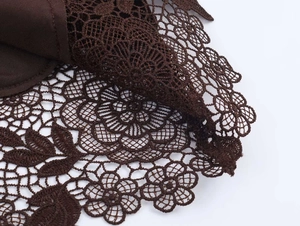 Close-up of dark brown floral lace fabric with intricate crochet details and hollow texture