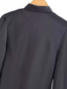Detail view of black satin long sleeve shirt back with pleated shoulders on wooden hanger